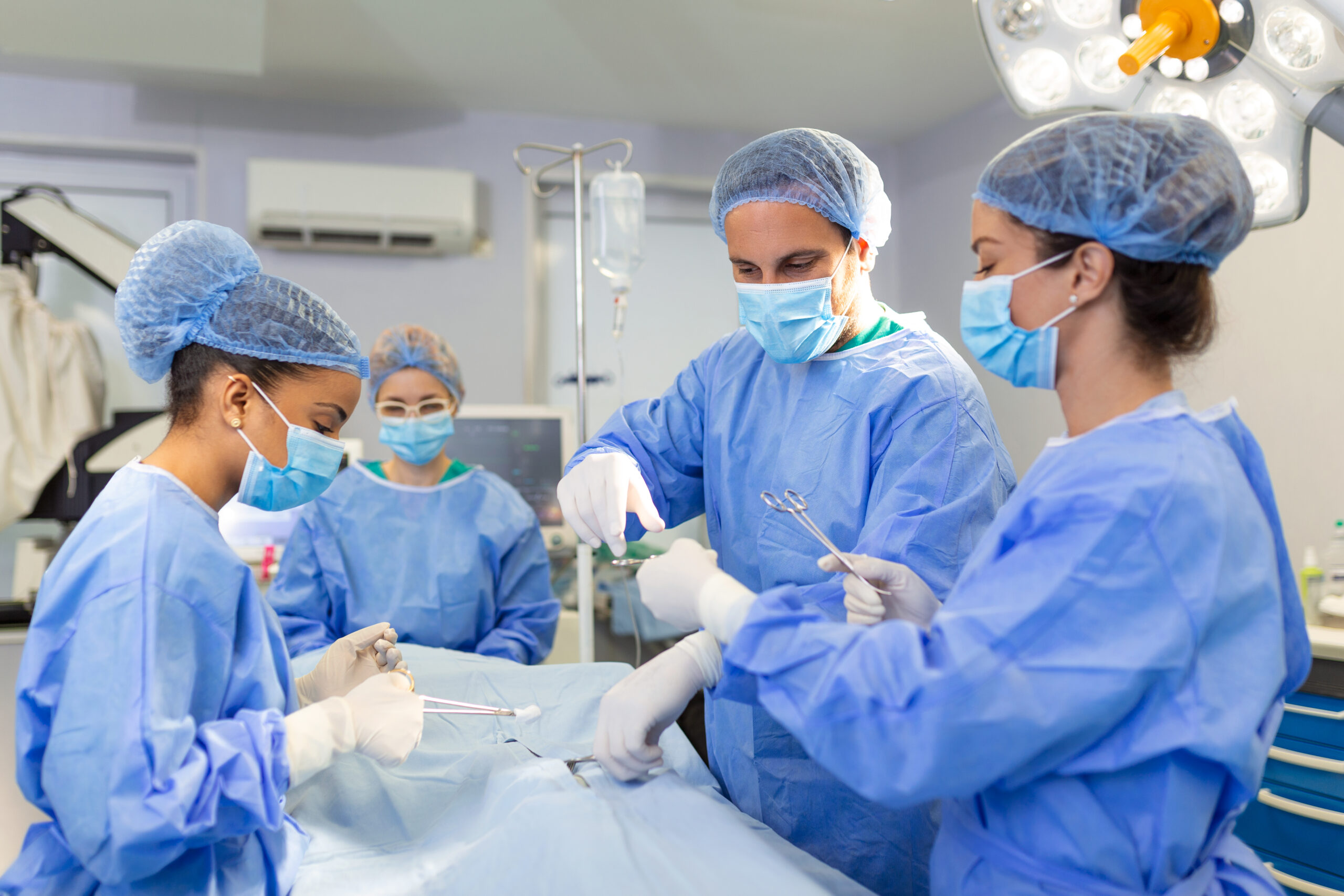 Diverse Team of Professional surgeon, Assistants and Nurses Performing Invasive Surgery on a Patient in the Hospital Operating Room. Surgeons Talk and Use Instruments. Real Modern Hospital