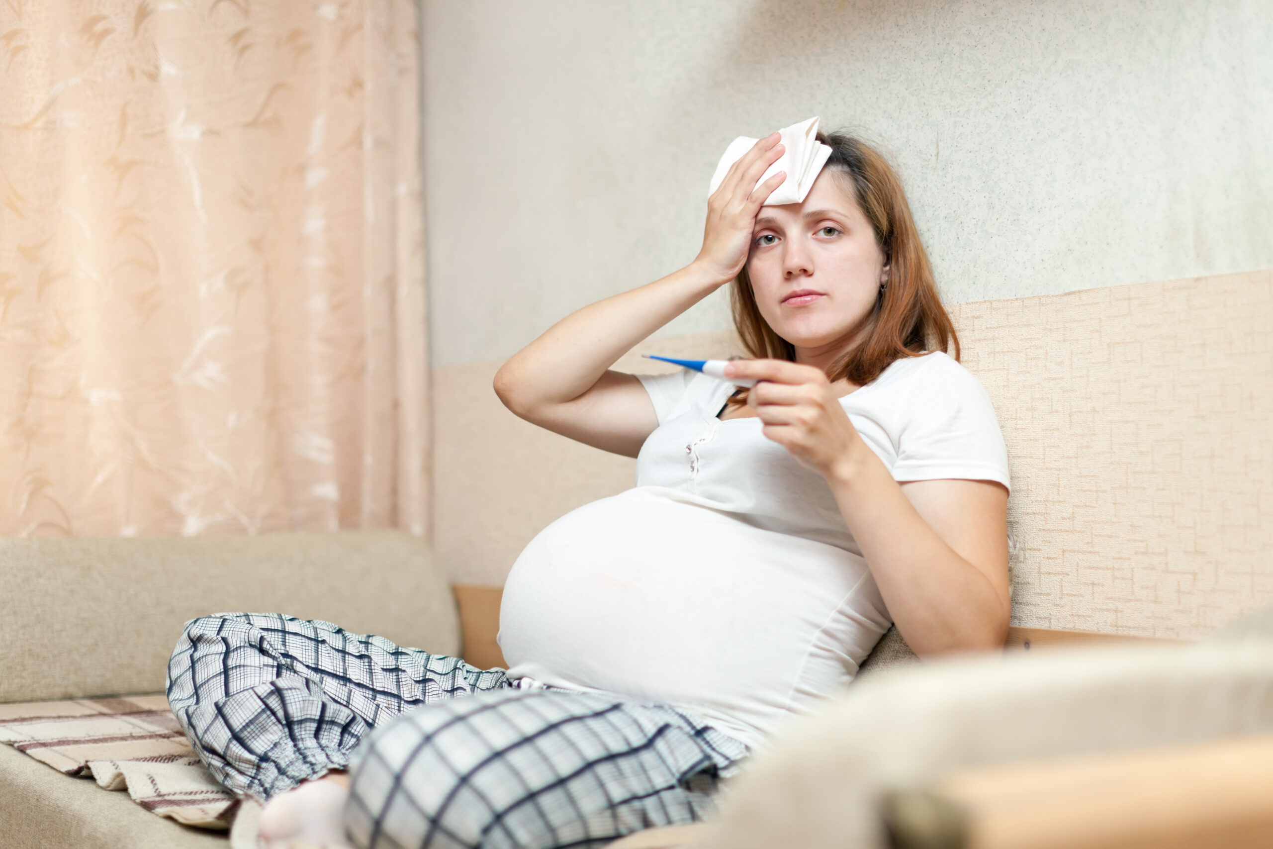 pregnant woman with thermometer in living room